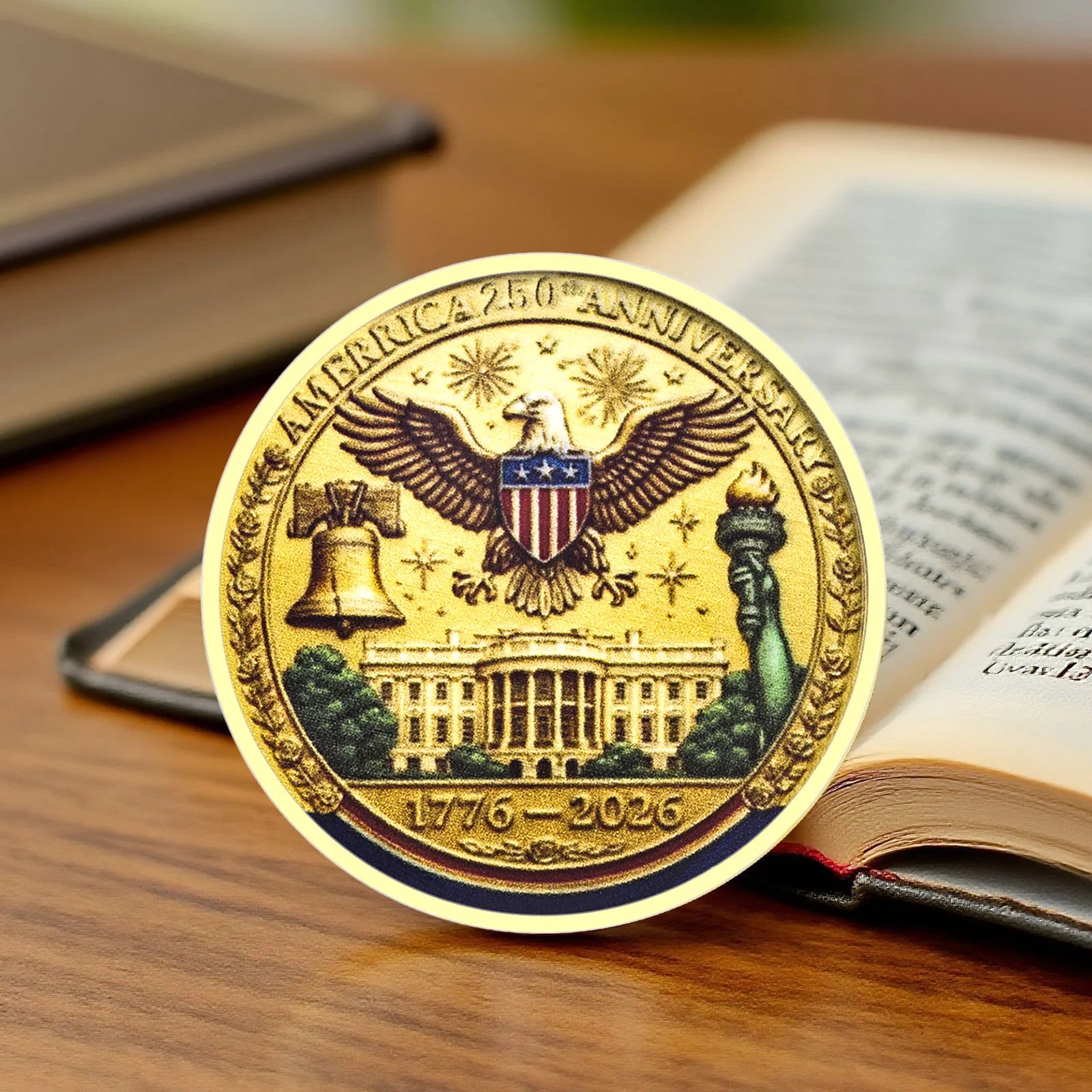 Gold coin commemorating America's 250th anniversary on a wooden surface with an open book.